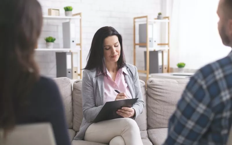 Professional psychologist taking notes at couple meeting with patients